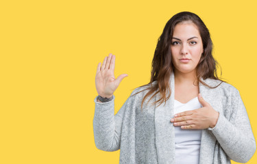 Beautiful plus size young woman wearing winter jacket over isolated background Swearing with hand...