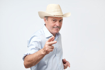 mature man wearing cowboy in studio. He is looking at camera with confidence