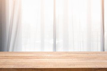 Empty of wood table with Blur of curtain window in living room with sunlight.