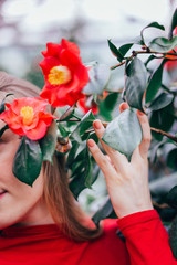 The girl presses a branch with blooming red flowers to her face