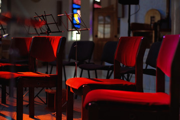Empty places for orchestra on stage. The chairs are lit by red and blue light floodlights.