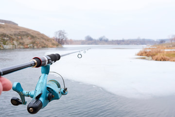 Fishing rod, wheel, fisherman fishing spinning on the background river