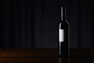 Wine bottle with blank label on wooden surface on dark