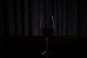 Silhouette of glass with burgundy red wine on dark