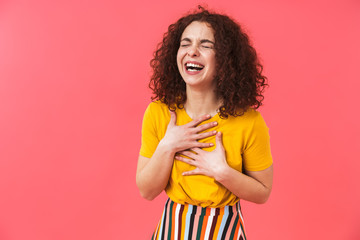 Cute happy beautiful young curly girl posing isolated over red wall background.