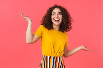 Cute happy beautiful young curly girl posing isolated over red wall background.