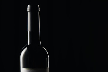 Bottle of wine with dark wrapper isolated on black