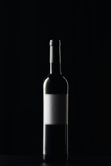 Wine bottle with blank label on dark surface isolated on black