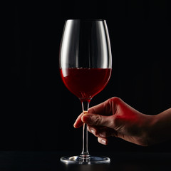 Cropped view of woman holding wine glass with red wine isolated on black