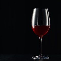 Wine glass with red wine on dark surface isolated on black