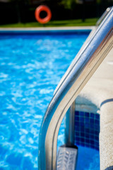 Staircase on the swimming pool edge with blue water copy space during a sunny summer day