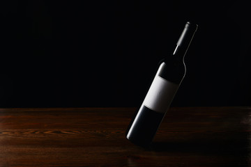 Wine bottle with blank label on wooden surface isolated on black