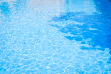 Closeup view of the swimming pool blue water surface copy space during a sunny summer day with tree shadows