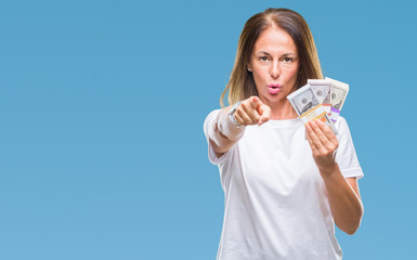 Middle age hispanic woman holding bunch of dollars over isolated background pointing with finger to the camera and to you, hand sign, positive and confident gesture from the front