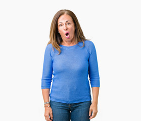 Middle age beautiful woman wearing winter sweater over isolated background In shock face, looking...