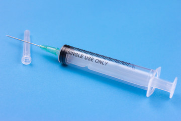 Disposable syringe and its packaging on a blue background