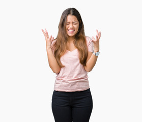 Obraz premium Young beautiful brunette woman wearing pink t-shirt over isolated background celebrating mad and crazy for success with arms raised and closed eyes screaming excited. Winner concept
