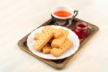 Scottish shortbread butter cookies on a vintage tray with a cup of tea, a jar of jam, and copy space