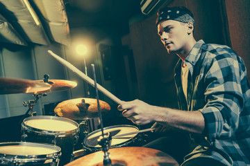 selective focus of handsome drummer holding drum sticks while playing drums
