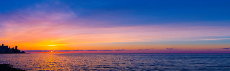 Sunset over Malecon and Atlantic Ocean with residential building in background - Havana, Cuba 