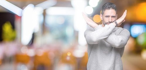 Young handsome man wearing sweatshirt over isolated background Rejection expression crossing arms doing negative sign, angry face