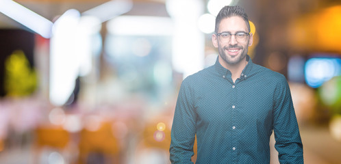 Young handsome business man wearing glasses over isolated background with a happy and cool smile on face. Lucky person.