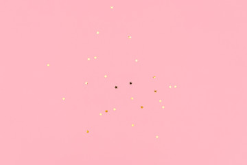 Golden sparkles on pink pastel trendy background. Festive backdrop for your projects.
