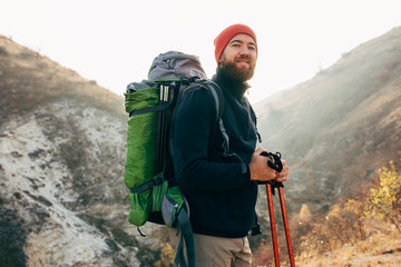 Horizontal outdoors portrait of hiker young male hiking in mountains with travel backpack. Happy...