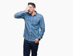 Young handsome man over isolated background peeking in shock covering face and eyes with hand, looking through fingers with embarrassed expression.