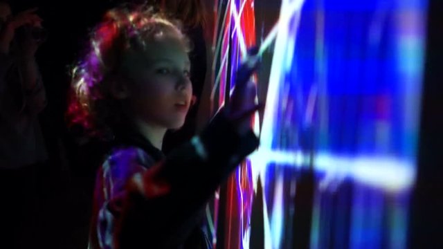 Young boy playing with led light interaction wall. Abstract pattern, new technologies, futuristic projects