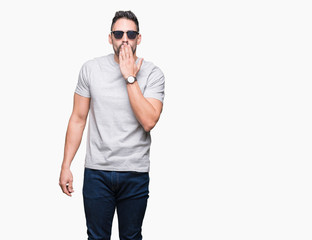 Fototapeta premium Young handsome man wearing sunglasses over isolated background cover mouth with hand shocked with shame for mistake, expression of fear, scared in silence, secret concept