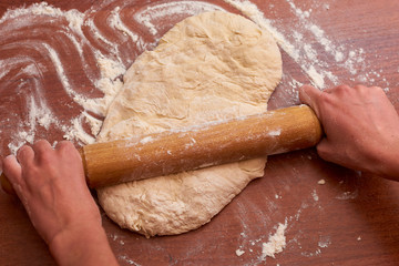 Dough for pizza. Rolling pin and dough on wooden background