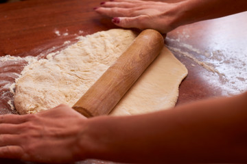 Dough for pizza. Rolling pin and dough on wooden background