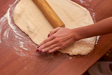 Dough for pizza. Rolling pin and dough on wooden background
