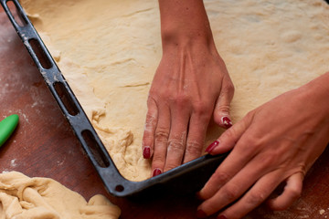 Dough for pizza. Rolling pin and dough on wooden background