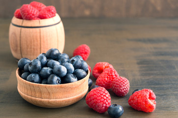 wild berries, raspberries and blueberries on a brown background.