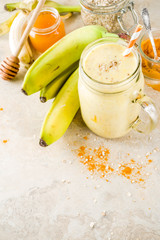 Healthy breakfast, snack. Trendy smoothie cocktail with banana, oatmeal, honey and turmeric. Light concrete background