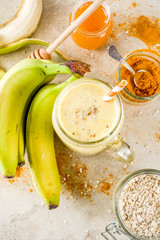 Healthy breakfast, snack. Trendy smoothie cocktail with banana, oatmeal, honey and turmeric. Light concrete background