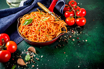 Italian lunch. Homemade spaghetti pasta with classic marinara tomato sauce, spices, garlic, basil. On a dark green concrete table copy space