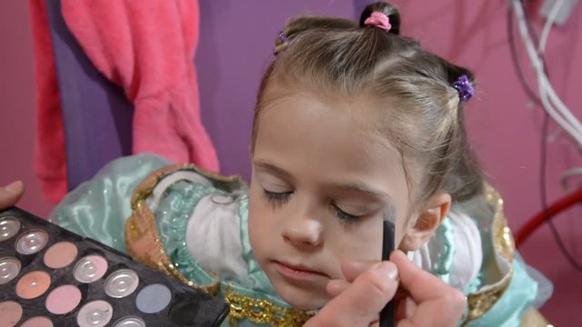 Do makeup to child. The mother paints the face of a little girl.