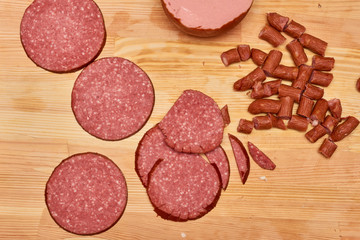 A variety of processed cold meat products, on a wooden cutting board