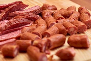 A variety of processed cold meat products, on a wooden cutting board