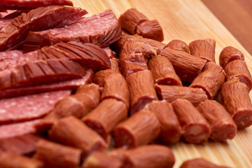 A variety of processed cold meat products, on a wooden cutting board