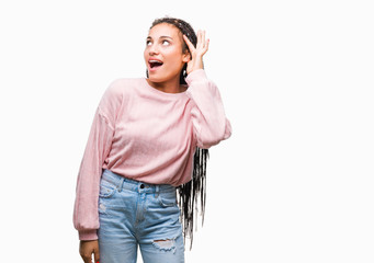 Fototapeta premium Young braided hair african american girl wearing sweater over isolated background smiling with hand over ear listening an hearing to rumor or gossip. Deafness concept.