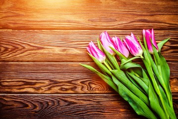 Bouquet of pink tulips on brown wooden background. 
