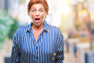 Obraz premium Atrractive senior caucasian redhead woman over isolated background afraid and shocked with surprise expression, fear and excited face.