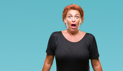 Atrractive senior caucasian redhead woman over isolated background afraid and shocked with surprise...