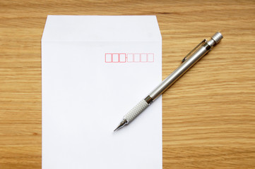 木の机の上に置かれた白い封筒とシャープペン