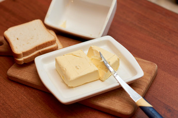 Piece of butter on white plate with knife