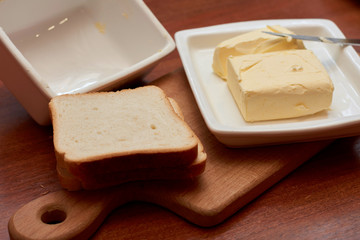 Piece of butter on white plate with knife